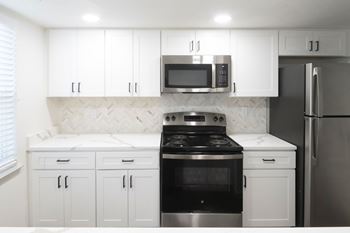A kitchen with white cabinets and a black stove top oven.